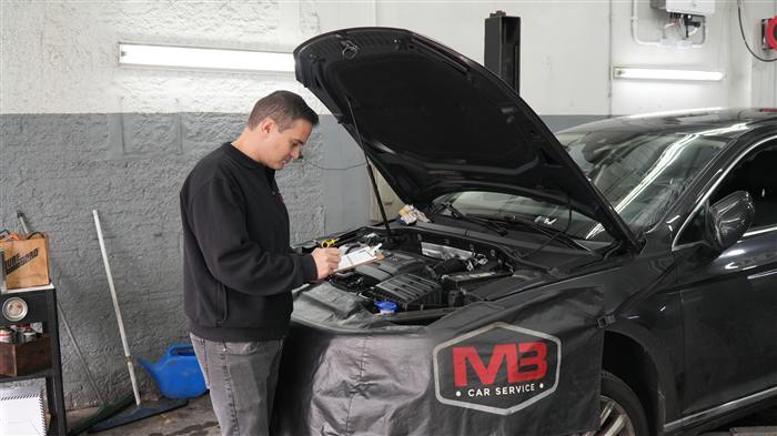 Mecânico realizando manutenção com capô aberto